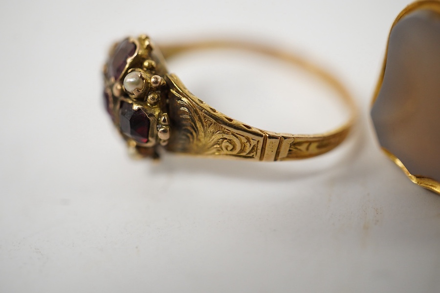 A group of four rings, comprising: a chalcedony signet ring with engraved floral shoulders, size L, partial British hallmarks for 15ct gold; a synthetic ruby and diamond five-stone ring, size N, stamped 18CT; a ring set